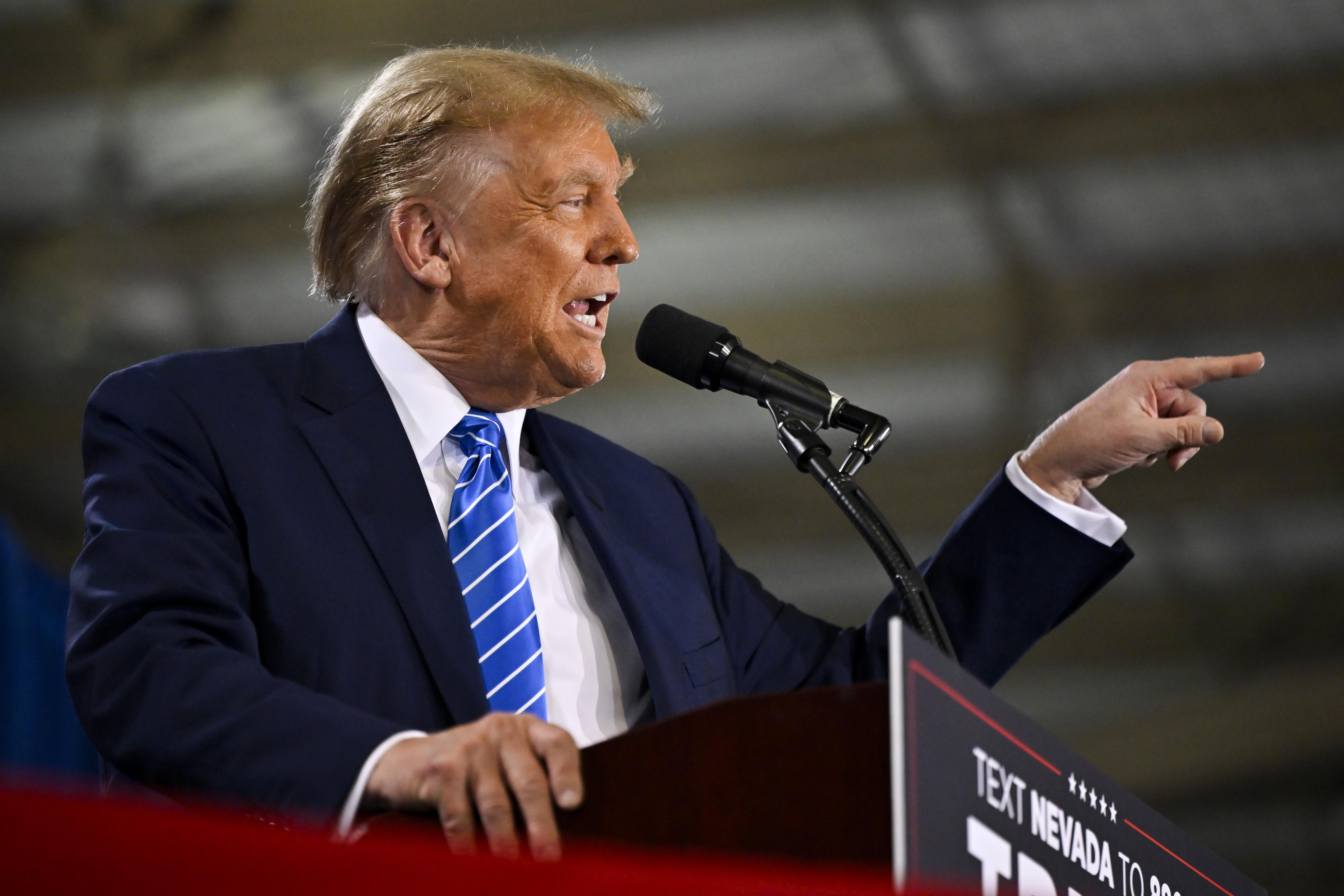 Trump gestures as he speaks into a microphone.