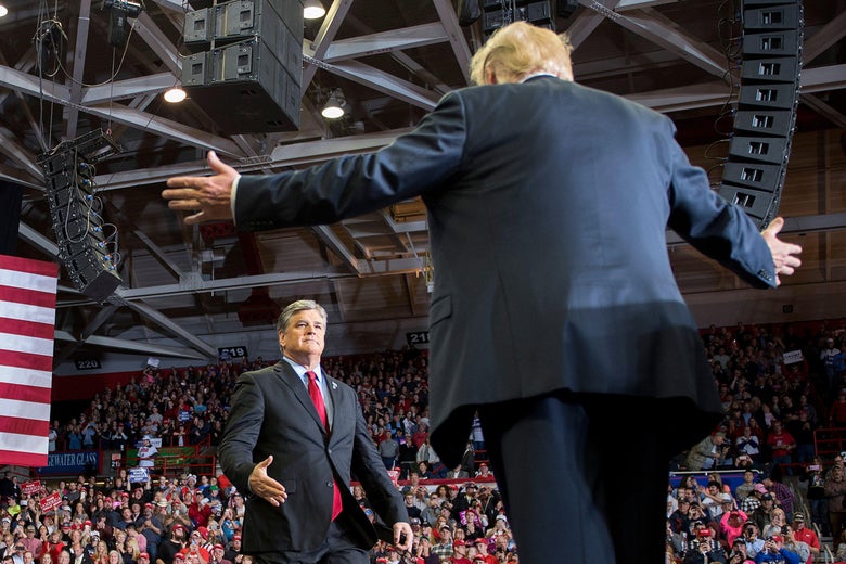 Trump extends his arms out to his sides as he walks toward Hannity onstage in the center of a packed arena