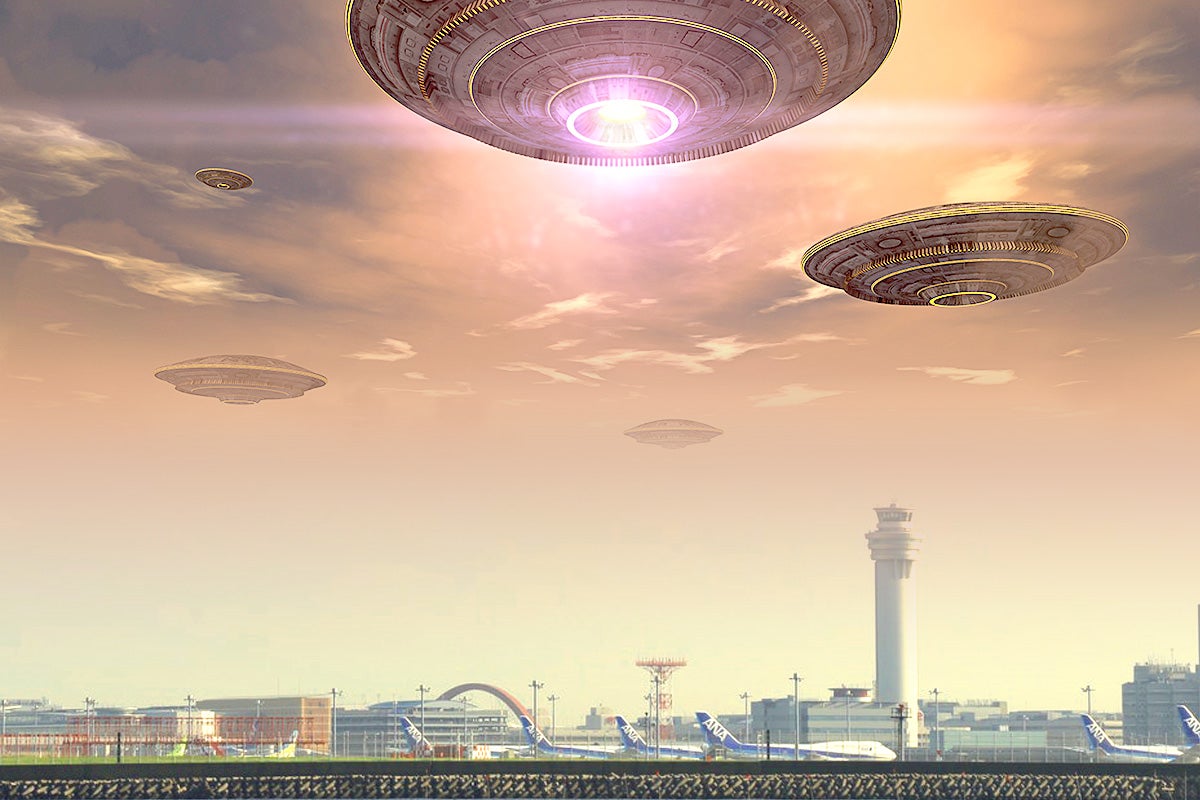 Photo illustration: A bunch of flying saucer-looking objects floating above an airport.