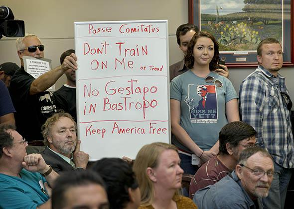 Bob Welch (standing at left) and Jim Dillon hold a sign at a public hearing about the Jade Helm 15 military training exercise in Bastrop, Texas, on April 27, 2015.