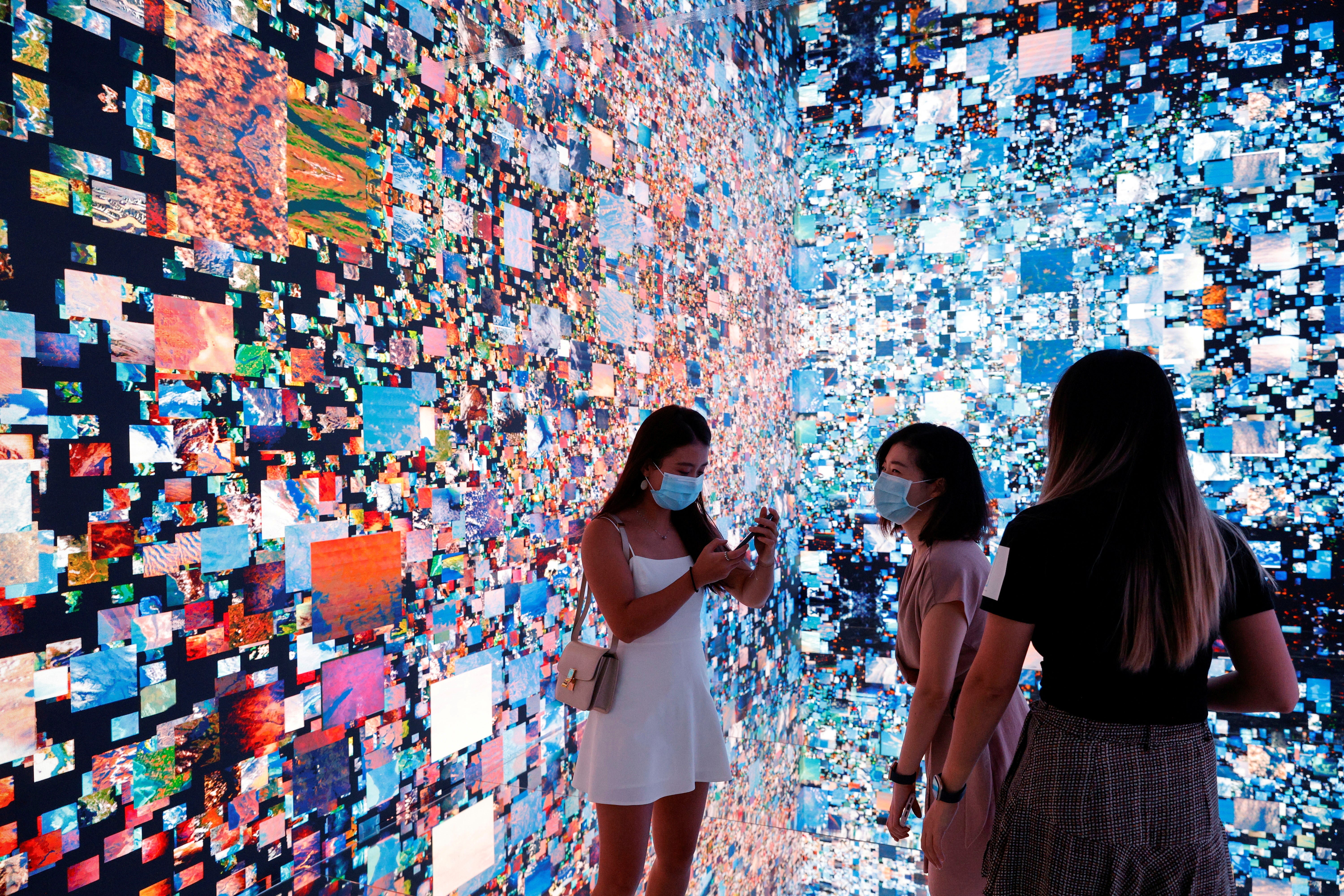 Visitors are pictured in front of an immersive art installation titled "Machine Hallucinations — Space: Metaverse" by media artist Refik Anadol