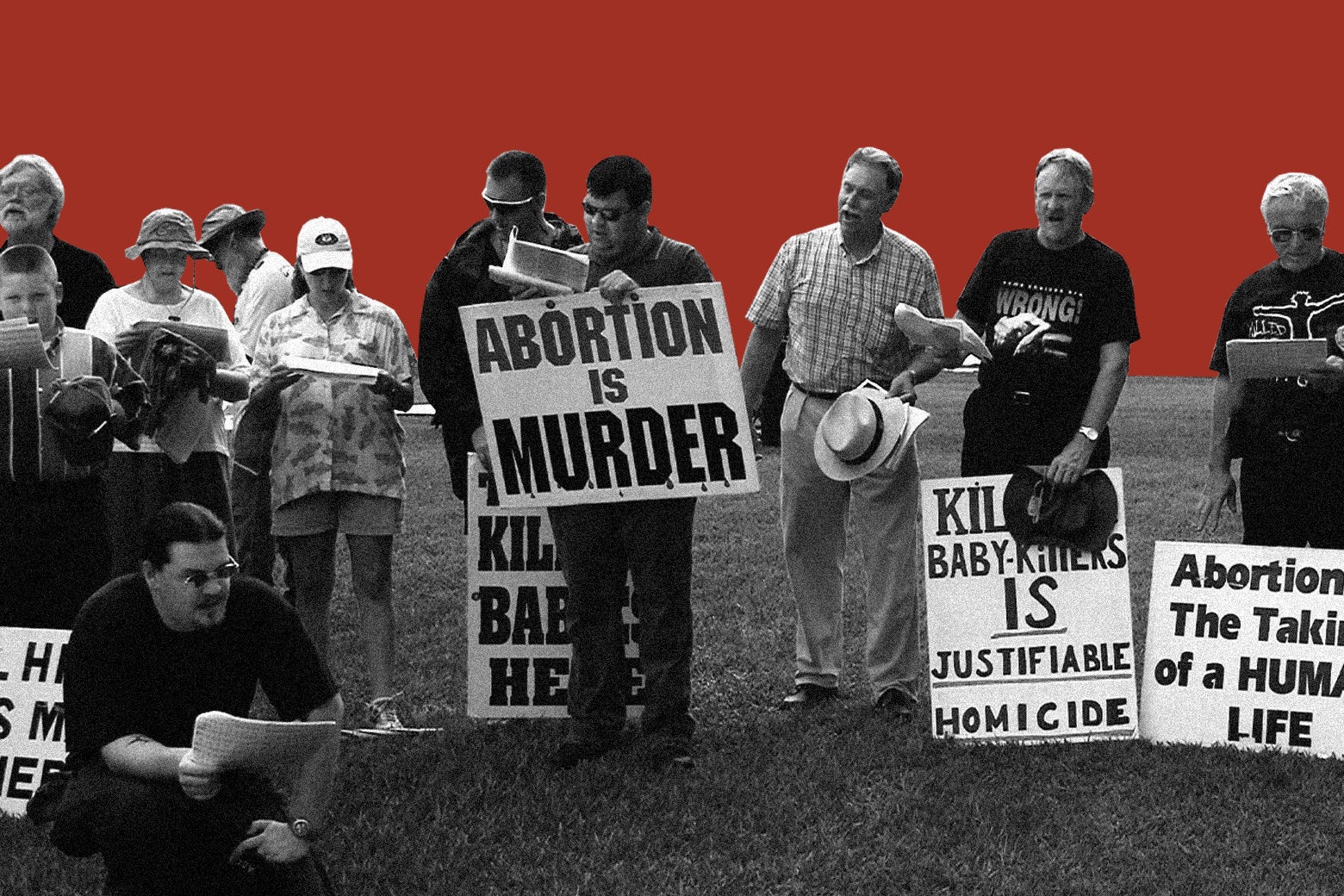 Anti-abortion protesters hold up signs saying "Abortion Is Murder" and "Killing Baby Killers Is Justifiable Homicide."