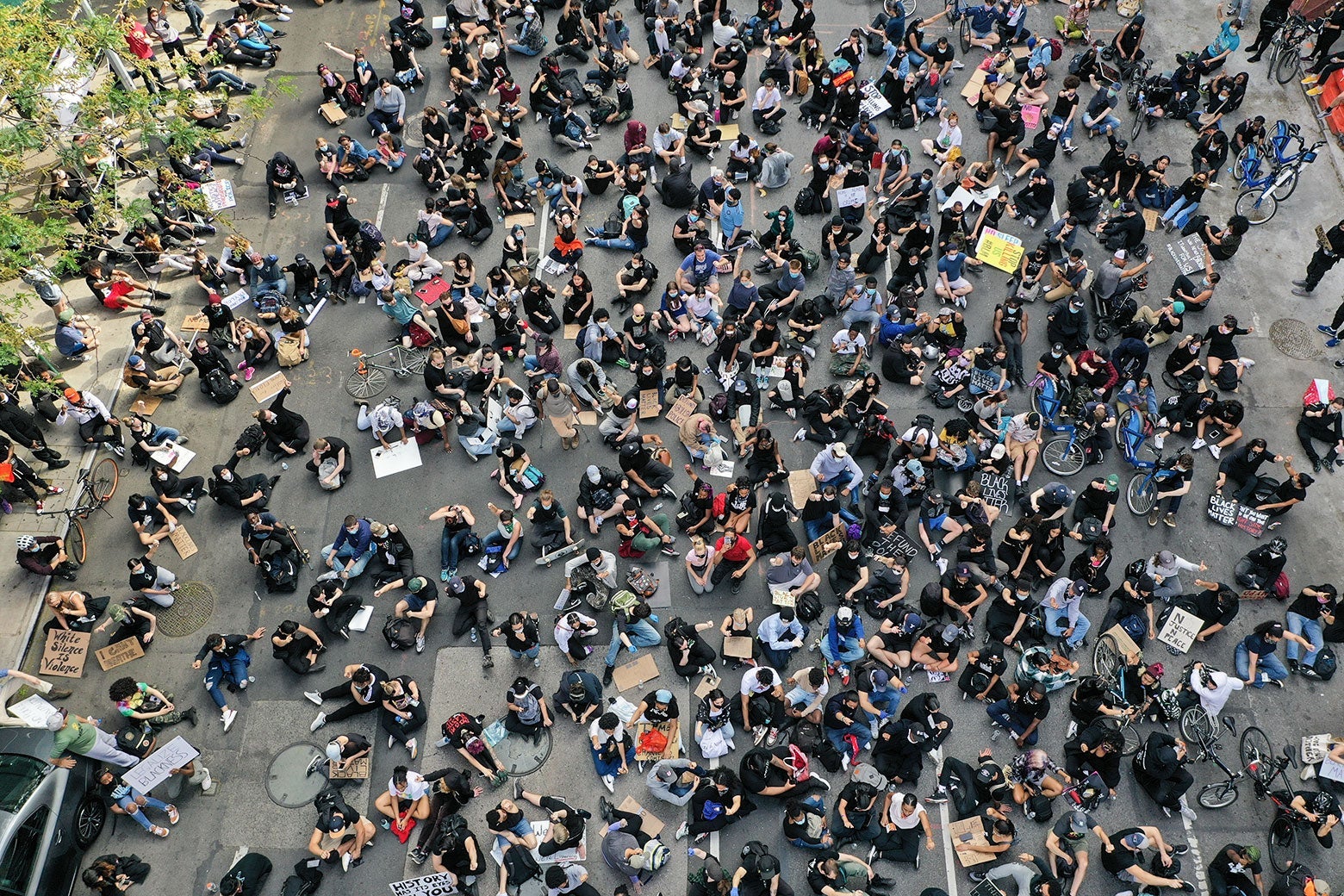 Protesters sit in the road, as seen from above.