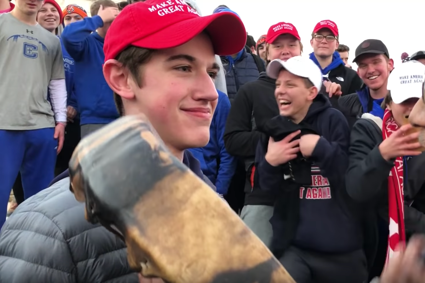 A group of teenage boys wearing MAGA hats taunting a Native American elder.