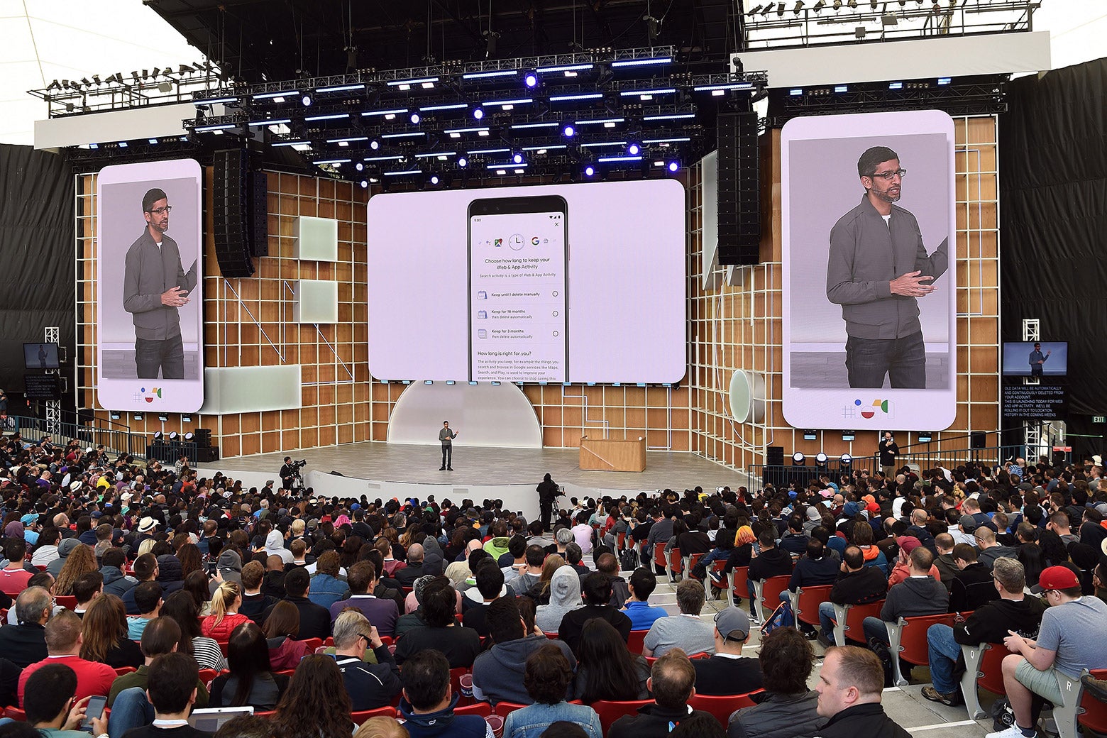 Sundar Pichai stands on a stage, flanked by images of himself on Android phones.