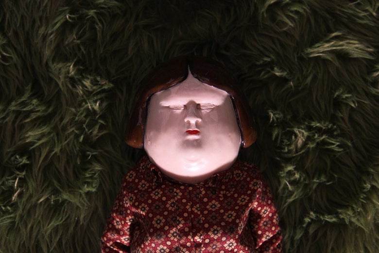In this still from the Oscar-nominated short film "Bestia," a porcelain-faced doll lies on its back in tall grass, eyes closed.