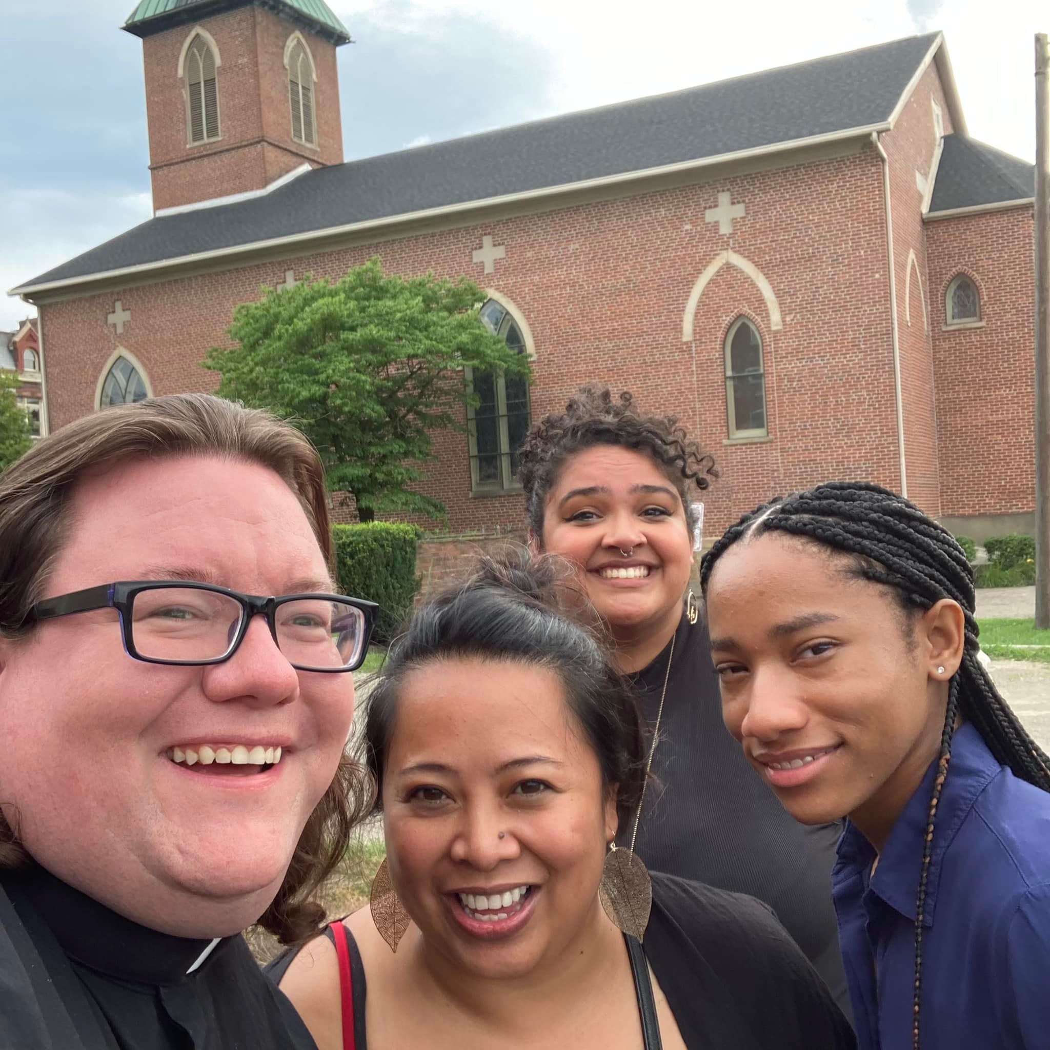 Ramsey with a priest and two other volunteers smiling together in front of their church