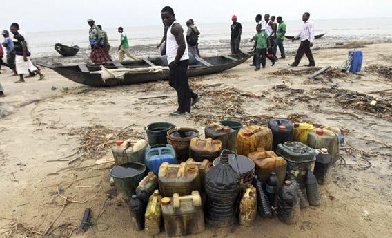 Villagers walk past jerrycans containing crude oil at the shore of the Atlantic ocean near Orobiri village, days after Royal Dutch Shell's Bonga off-shore oil spill in Nigeria's delta.