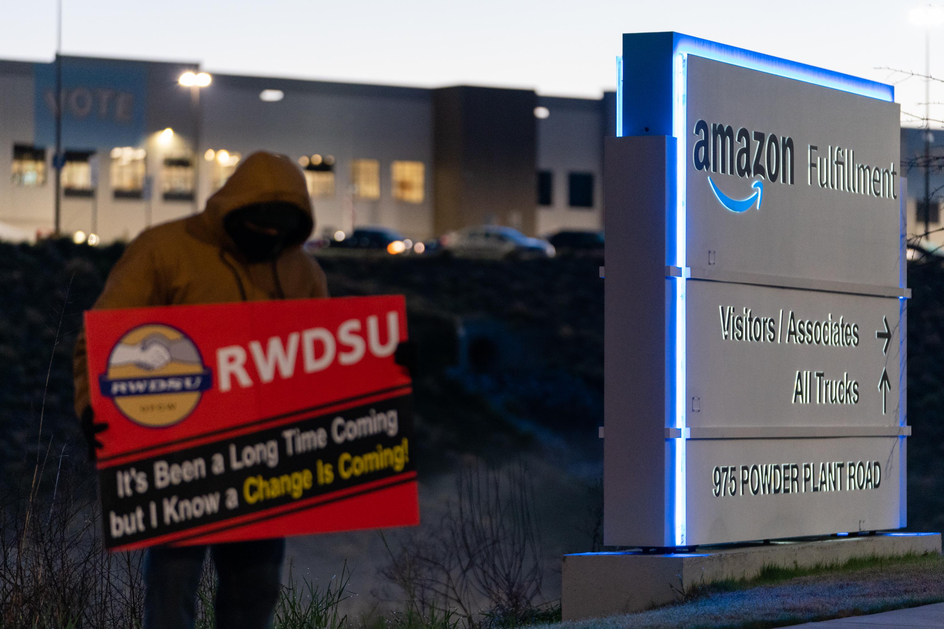 An RWDSU union rep holds a sign outside the Amazon fulfillment warehouse in Bessemer.