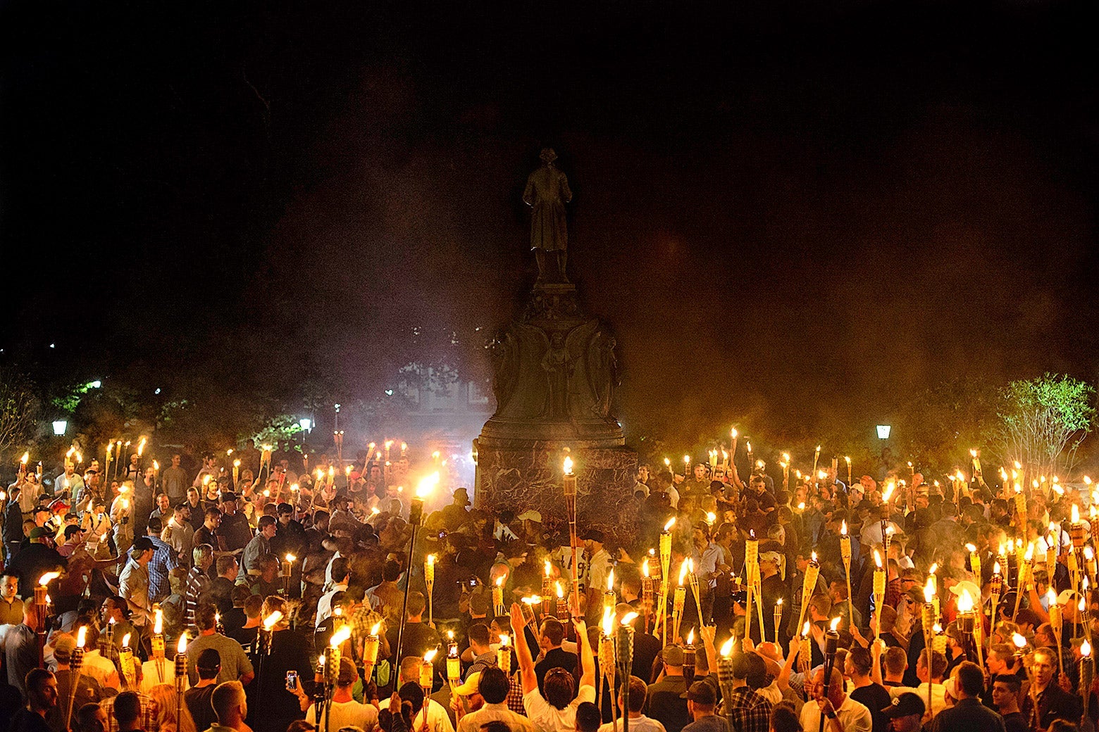 Alt-right protesters holding Tiki torches surround counterprotesters around a statue of Thomas Jefferson.