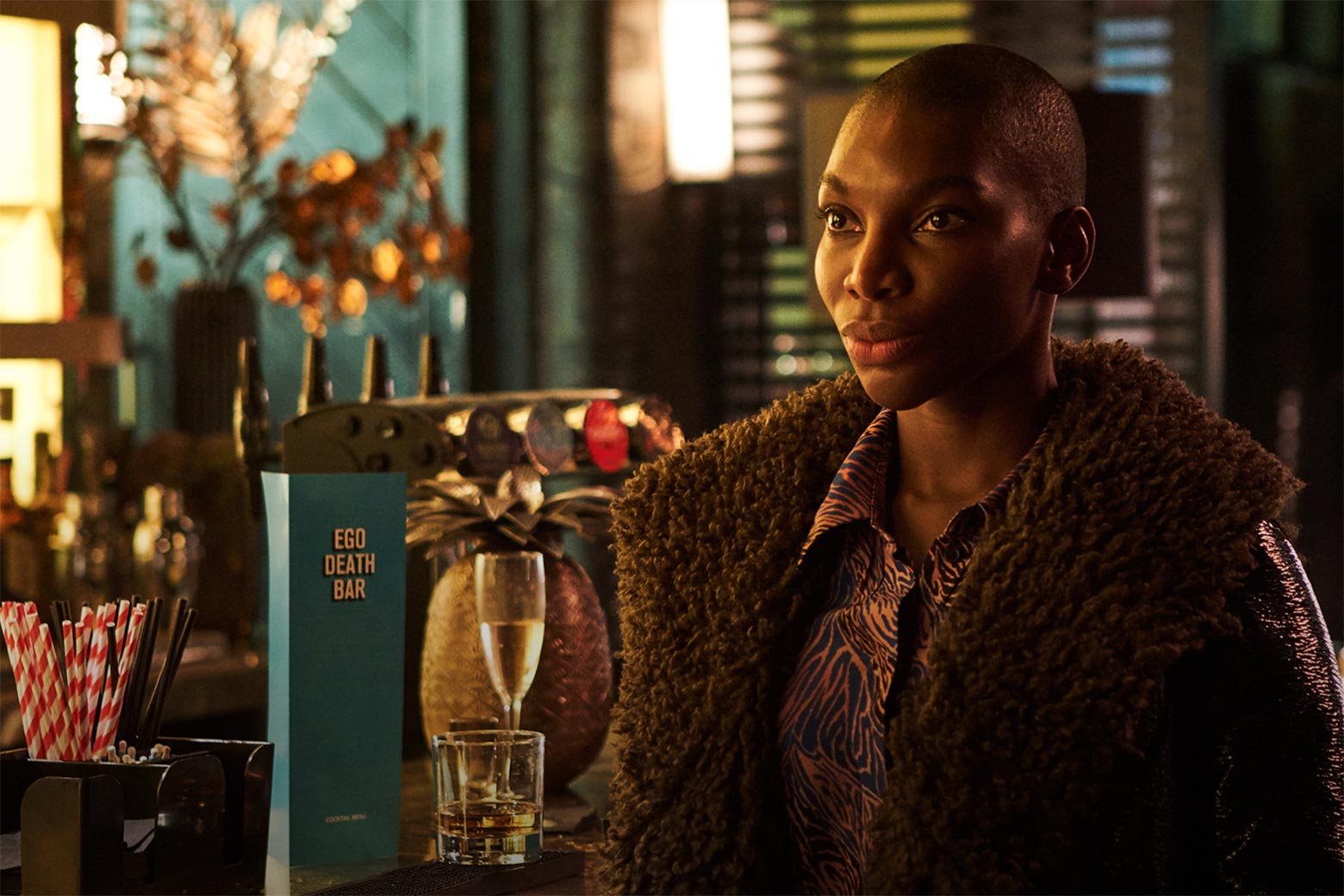 Black woman in a coat looking upset in front of a bar.