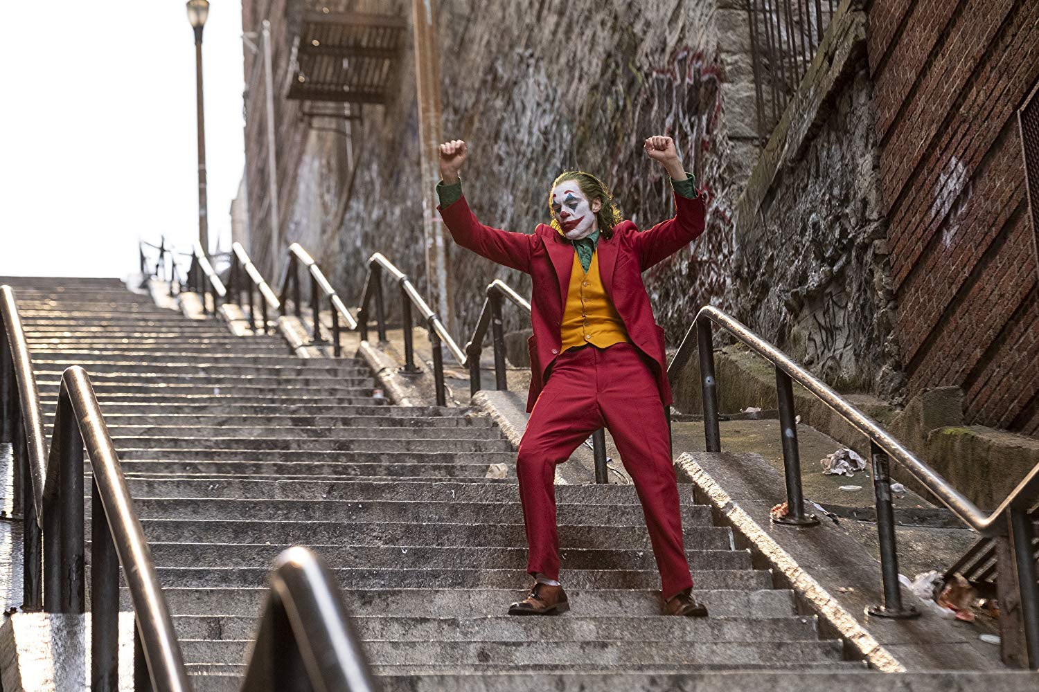 Joaquin Phoenix as the Joker, walking down a flight of stairs, in a still from Joker.
