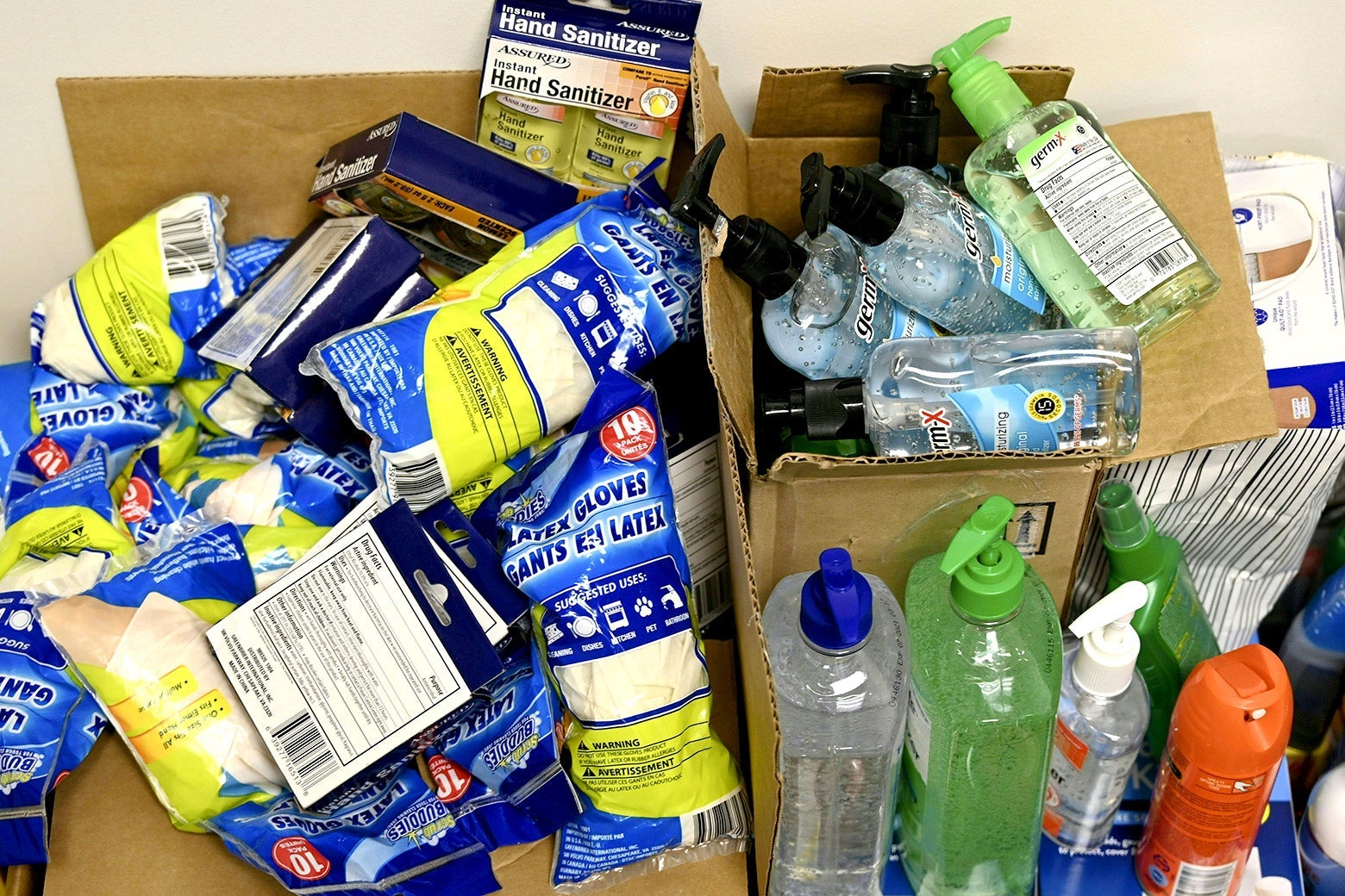 An assortment of cleaning supplies bursting from cardboard boxes.