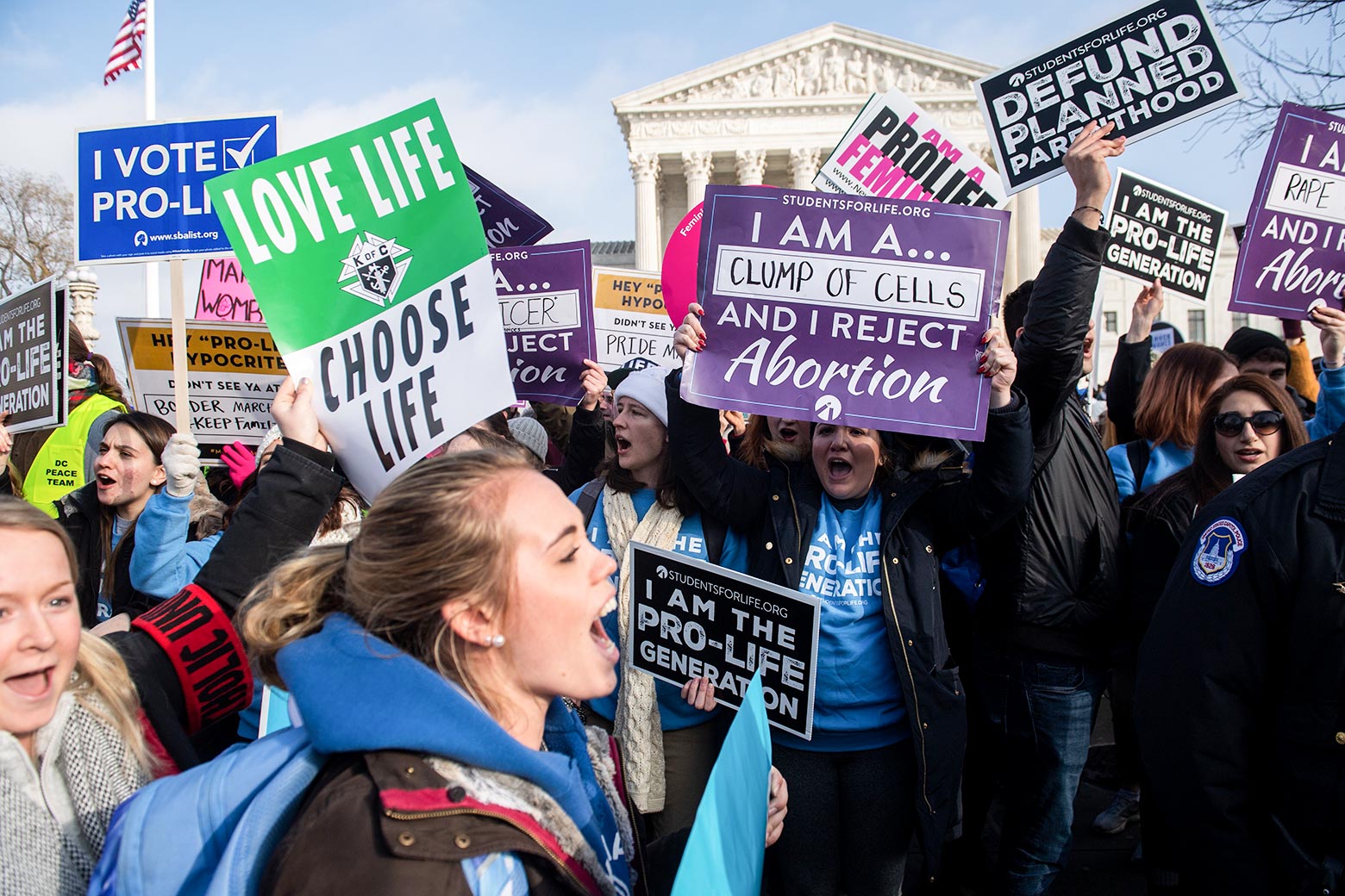 Anti-abortion protesters yell and hold up signs in front of the Supreme Court building.