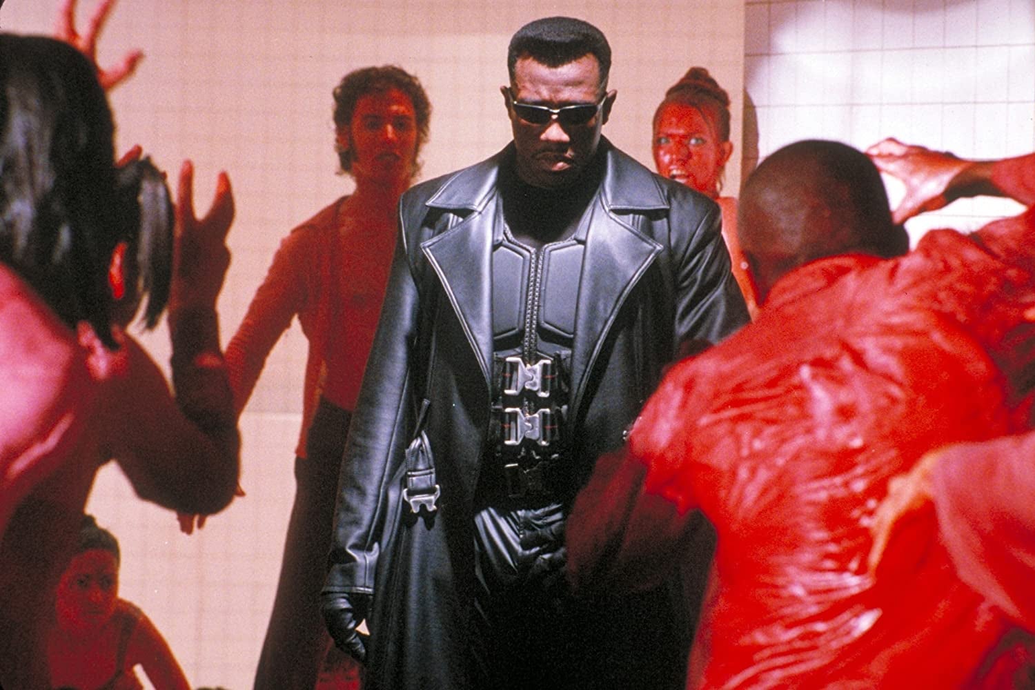 Wesley Snipes in a black leather trench coat is surrounded by red-clad figures.