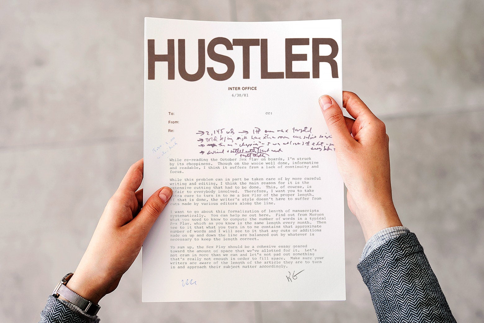 A pair of hands is seen clutching an inter-office memo from Hustler Magazine in the 1980s. The point of view is the man's, looking down at the paper in his hands.