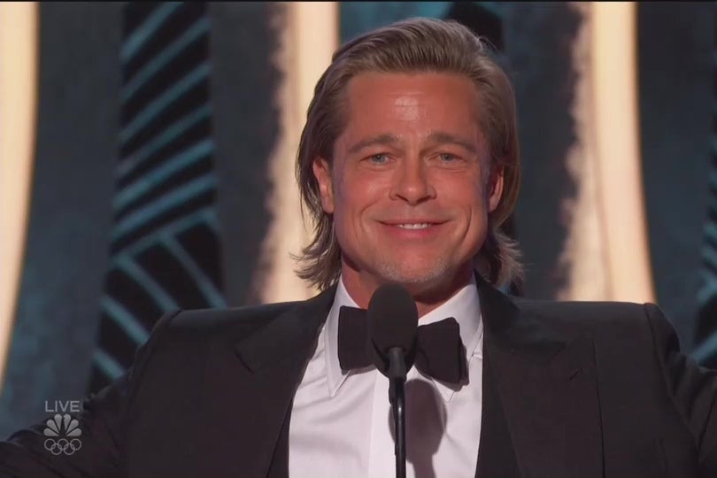 Brad Pitt in a tuxedo on the Golden Globes stage, smiling beatifically.