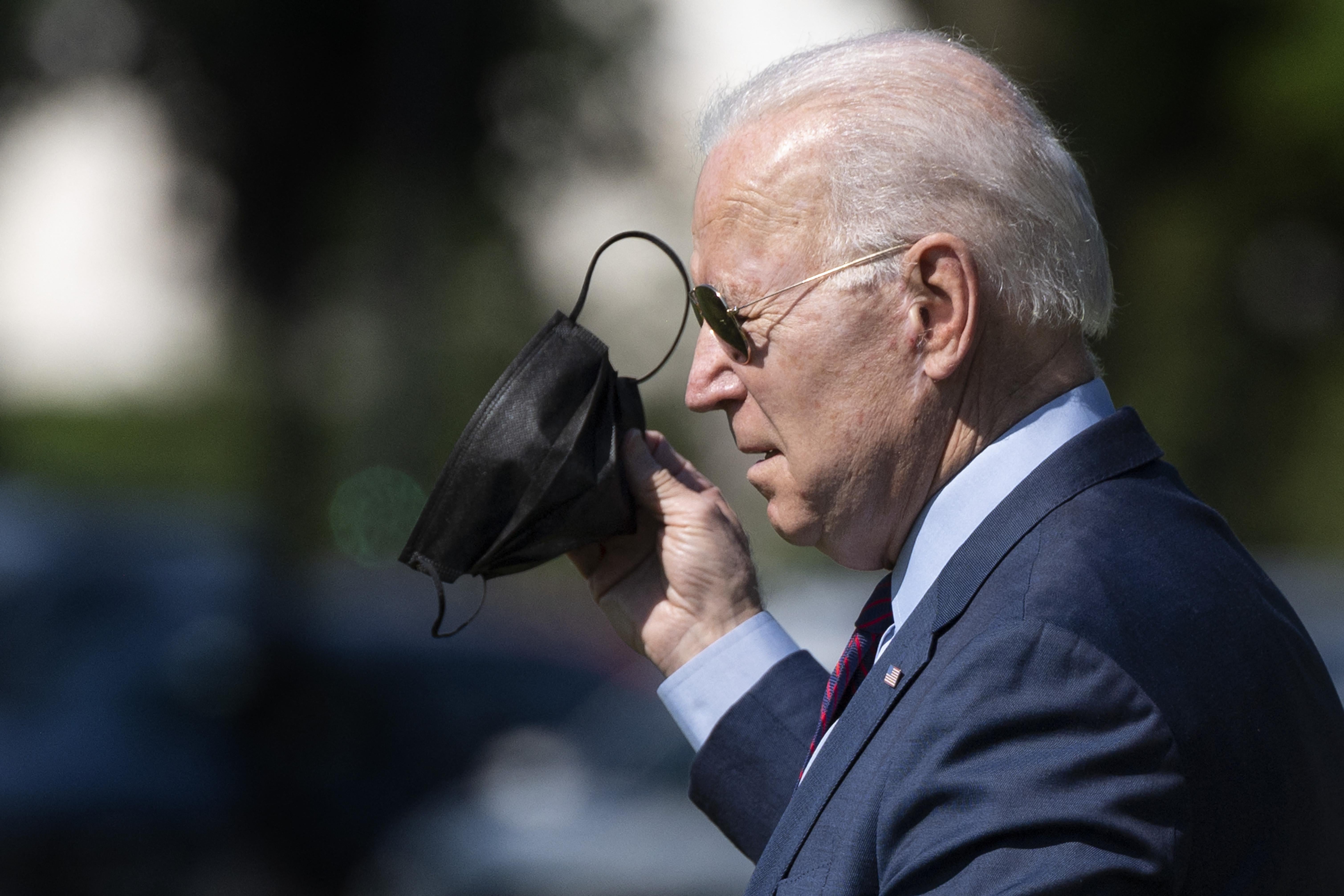 President Joe Biden removes his mask while wearing sunglasses outside