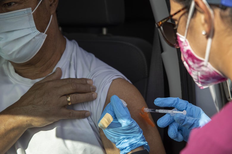 A healthcare worker administers a Pfizer-BioNTech COVID-19 vaccine to a person at a drive-thru site in Tropical Park on December 16, 2021 in Miami, Florida. 