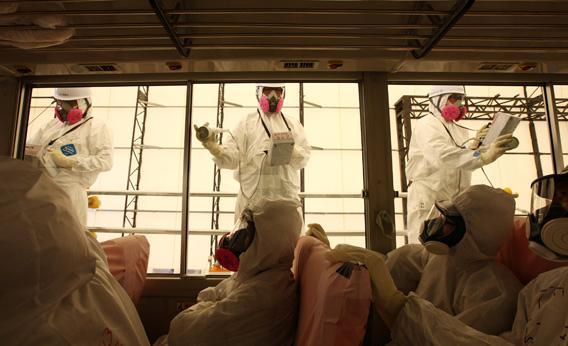 Workers carry out radiation screening on a bus for a media tour at Tokyo Electric Power Co.'s (Tepco) Fukushima Dai-Ichi nuclear power plant in Okuma Town, Fukushima Prefecture on May 26, 2012