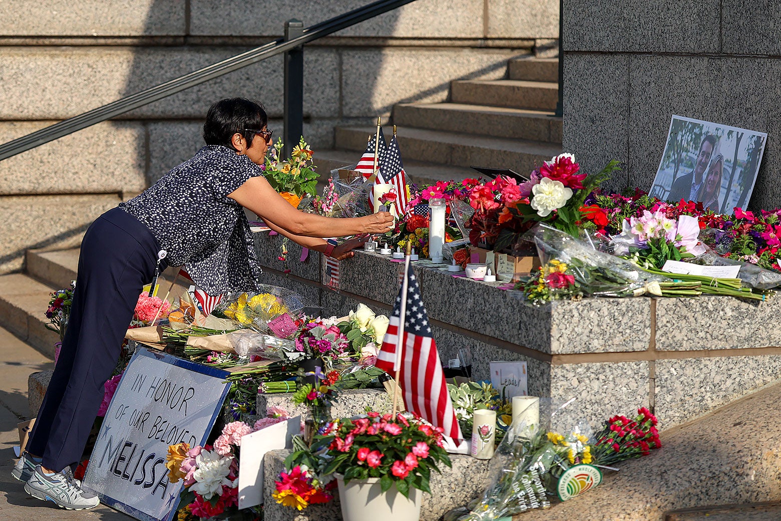 A woman lays flowers at a makeshift memorial for DFL State Rep. Melissa Hortman and her husband Mark Hortman at the Minnesota State Capitol building on Monday in St. Paul, Minnesota. 

