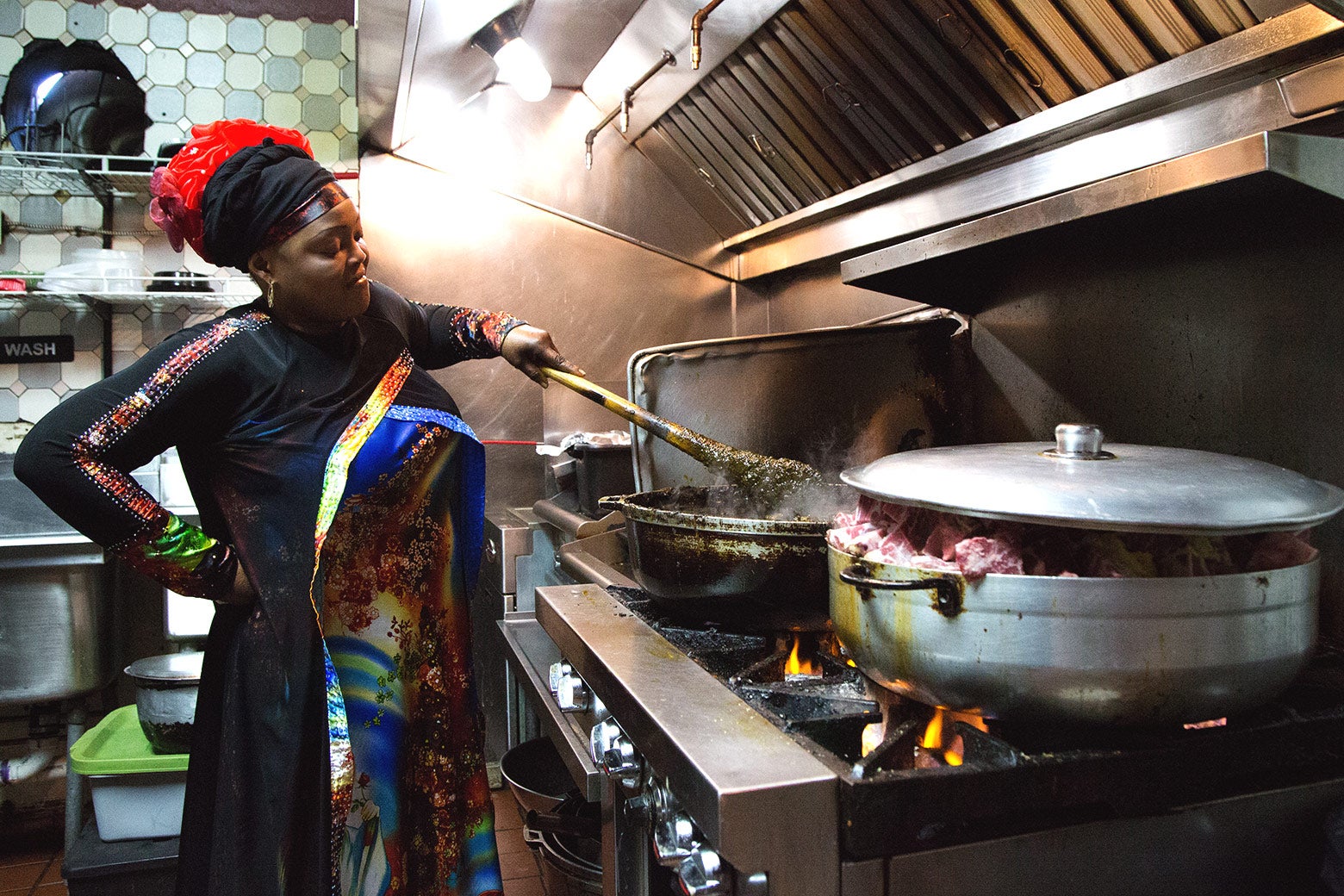 Fanta Fofana stirs a pot of cassava leaf stew in the kitchen of her restaurant, Le Mandingue.
