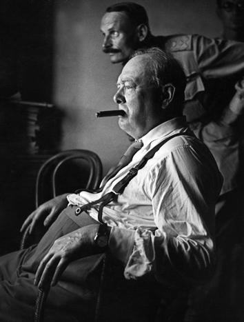 British Prime Minister Sir Winston Churchill, stripped to shirt sleeves and smoking a cigar, looks at enemy positions from a fortified forward position in Italy, 1944.