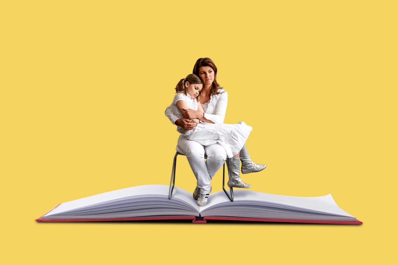 A woman sits on a chair and holds her daughter. The chair is on an open book.