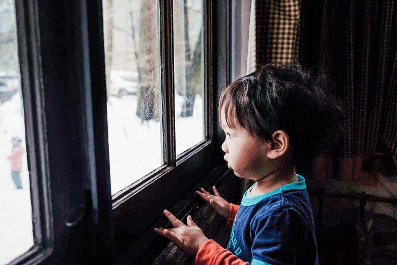 A young child looks out a large window.