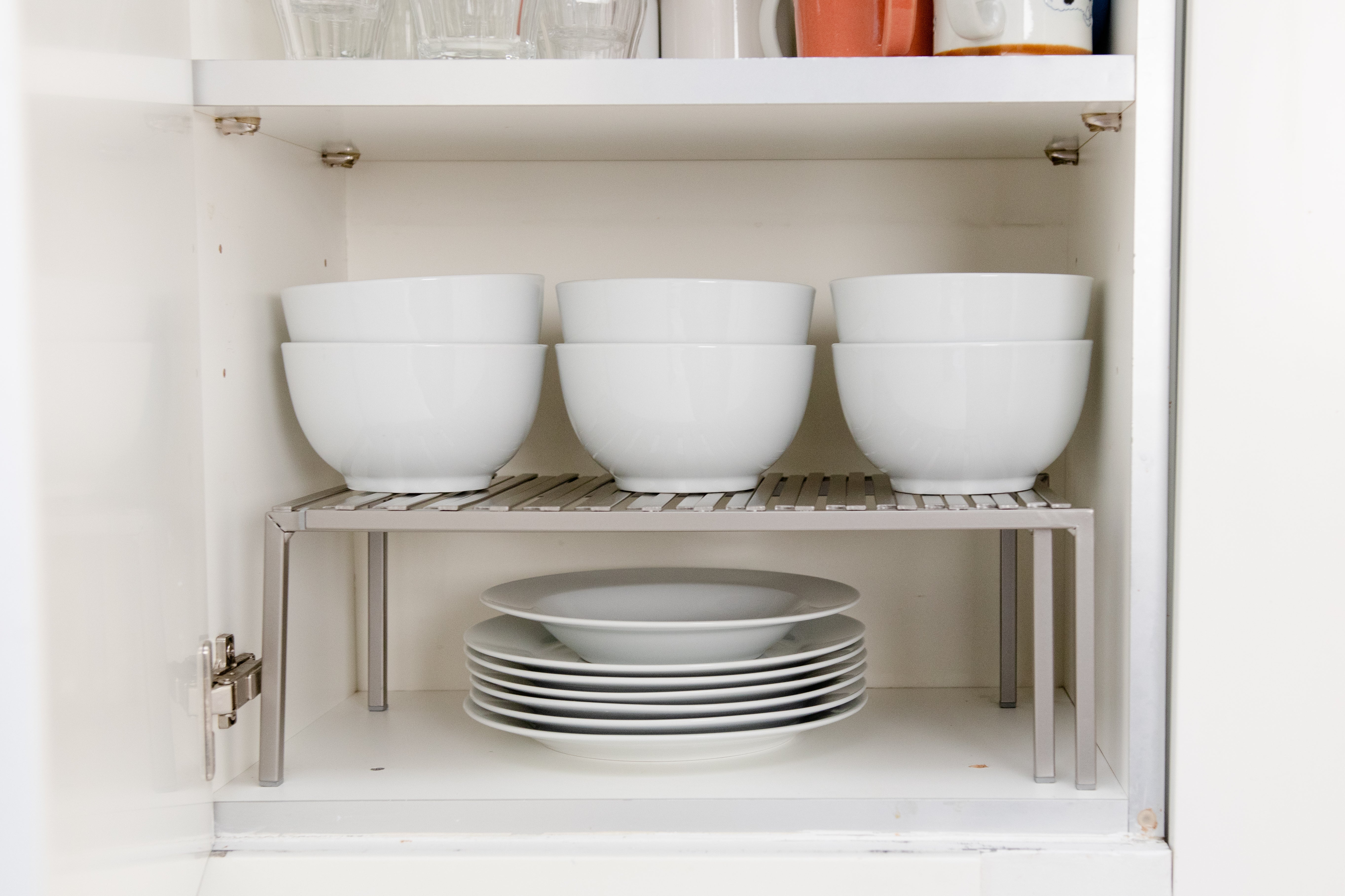 Shelf riser with dishes on it.