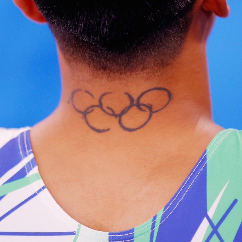 The back of Georgiou's neck showing the rings tattoo described below, the gymnast wearing a dynamic unitard with diagonal intersecting shapes and colors
