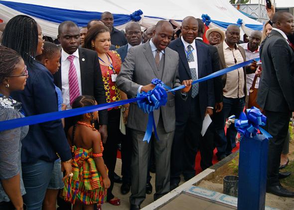 Governor Amaechi cuts the ribbon at the unveiling ceremony for a new water purification plant funded by Shell, flanked by government officials and representatives of Shell Nigeria.