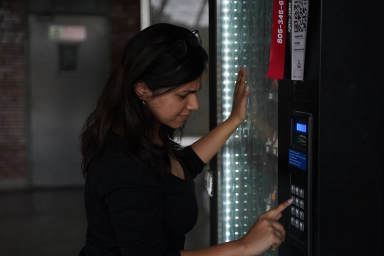 a woman selects something from a vending machine