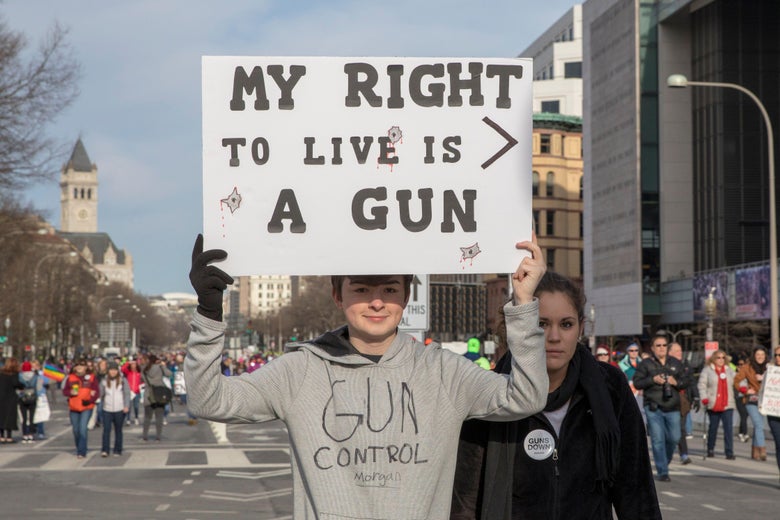 A young man holds a sign reading, "My right to life > a gun."