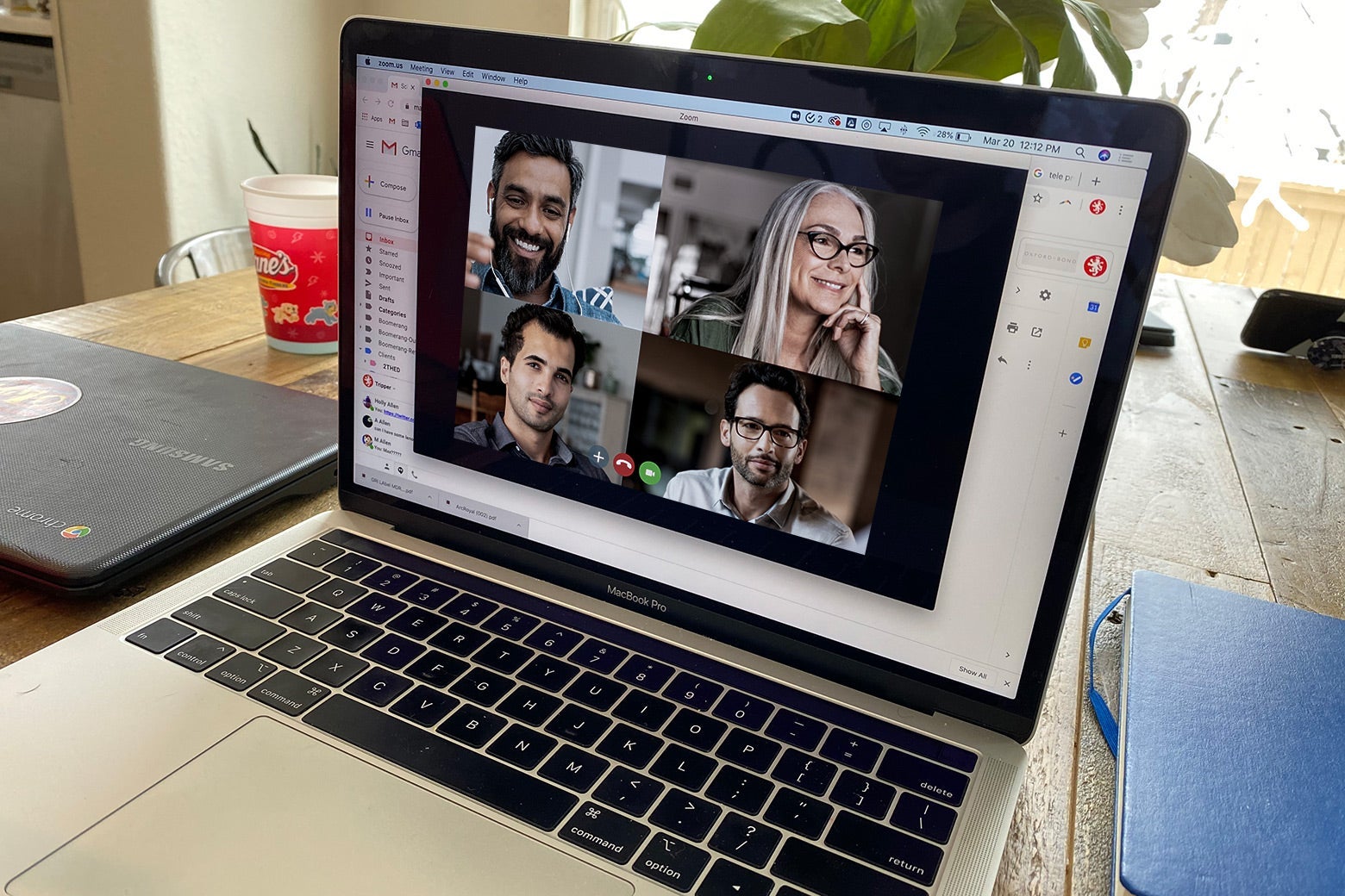 A laptop screen shows a Zoom call with four people on it.