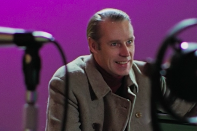 Smiling man in a peacoat with studio mic in the foreground