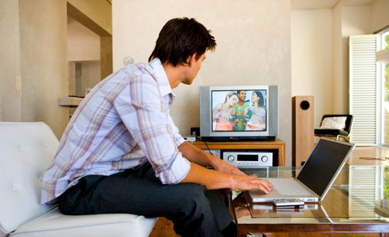 Man watching television with laptop.