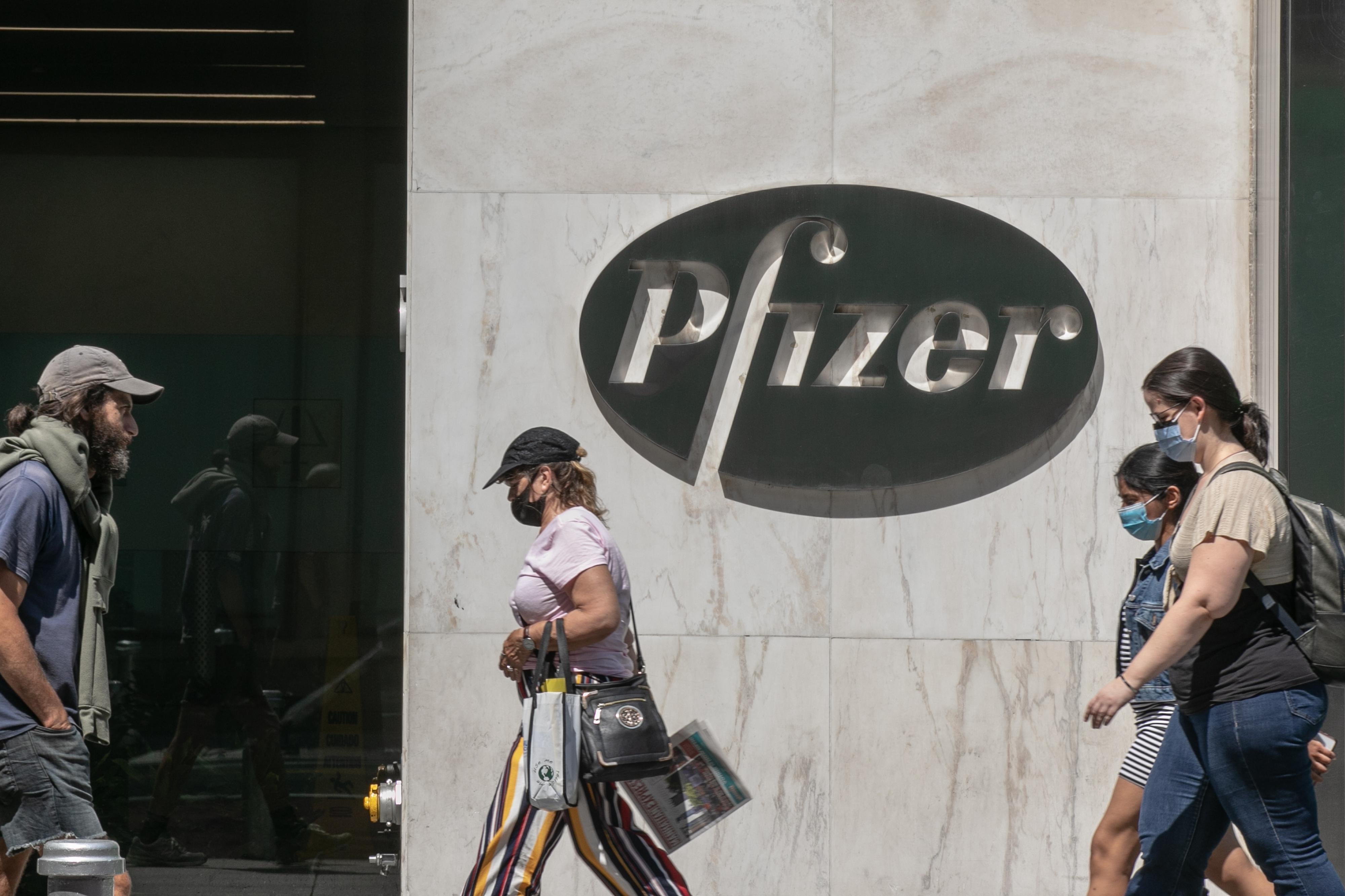 Pedestrians wearing protective masks walk past Pfizer Inc. headquarters in New York City.