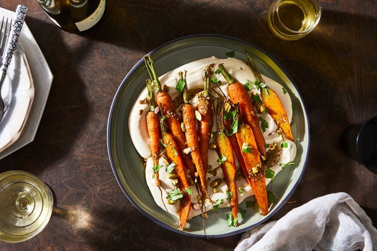 Roasted carrots and za’atar oil over hummus in a dish on a table