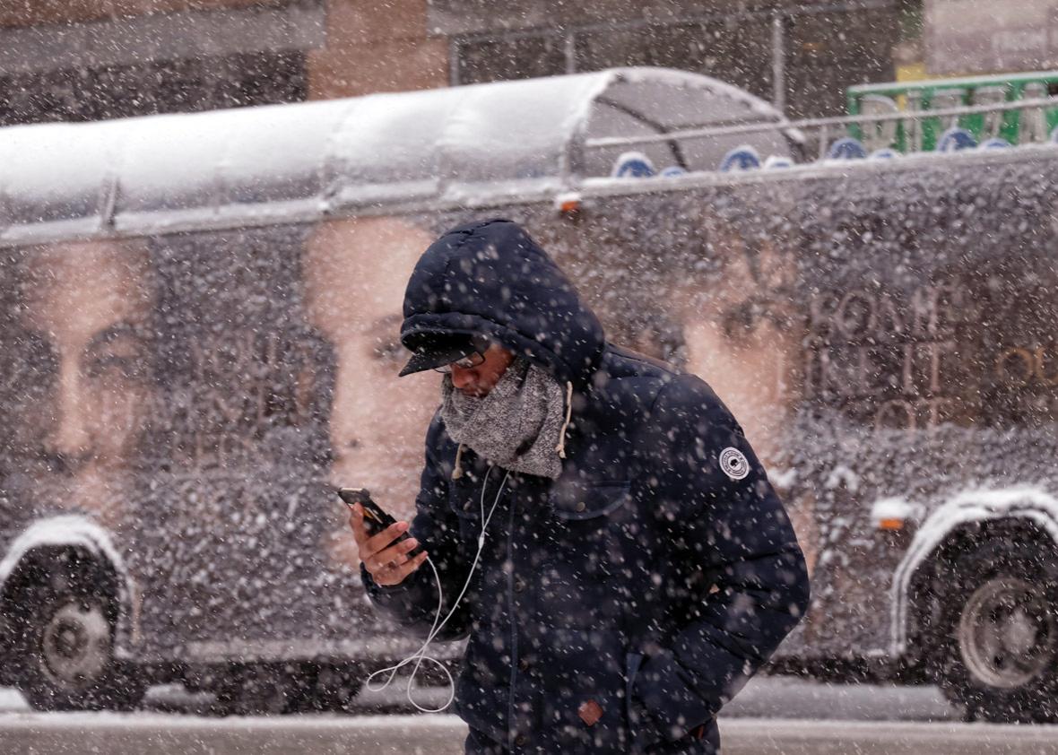 A man uses his smartphone as he crosses a street during a winter storm in New York on March 5, 2015.