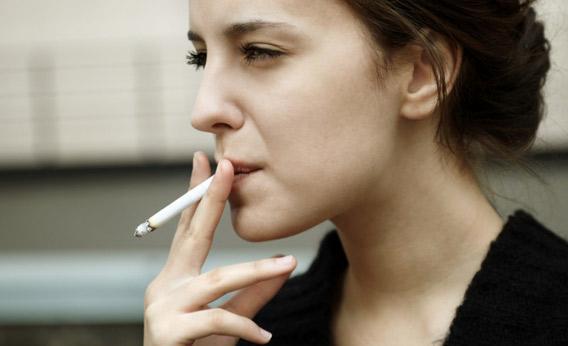 Woman smoking on a sidewalk.