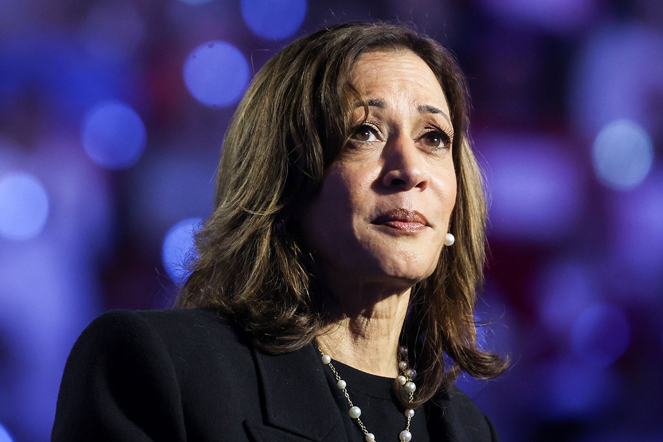 Kamala Harris looks so sad at the lectern with a wall of bright purple lights behind her.