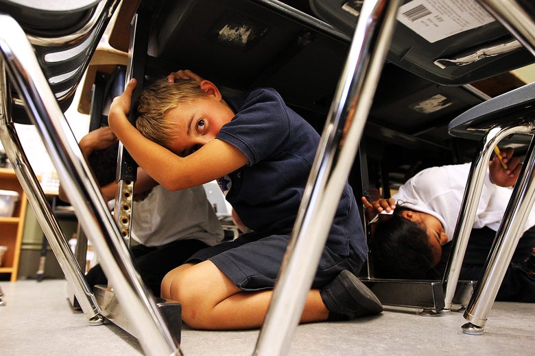 Students crouch under their desks covering their heads.