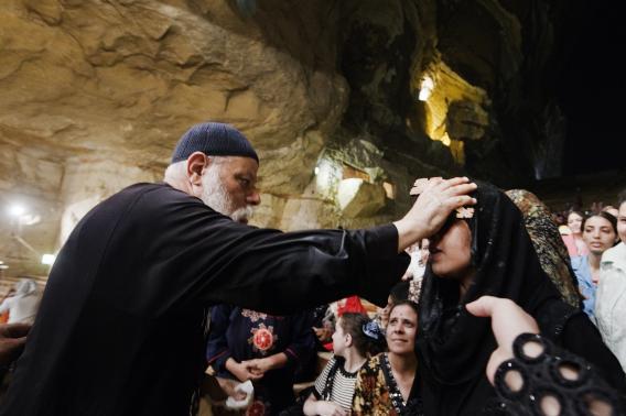 Coptic priest Father Samaan Ibrahim puts a cross on the forhead of an Egyptian woman.
