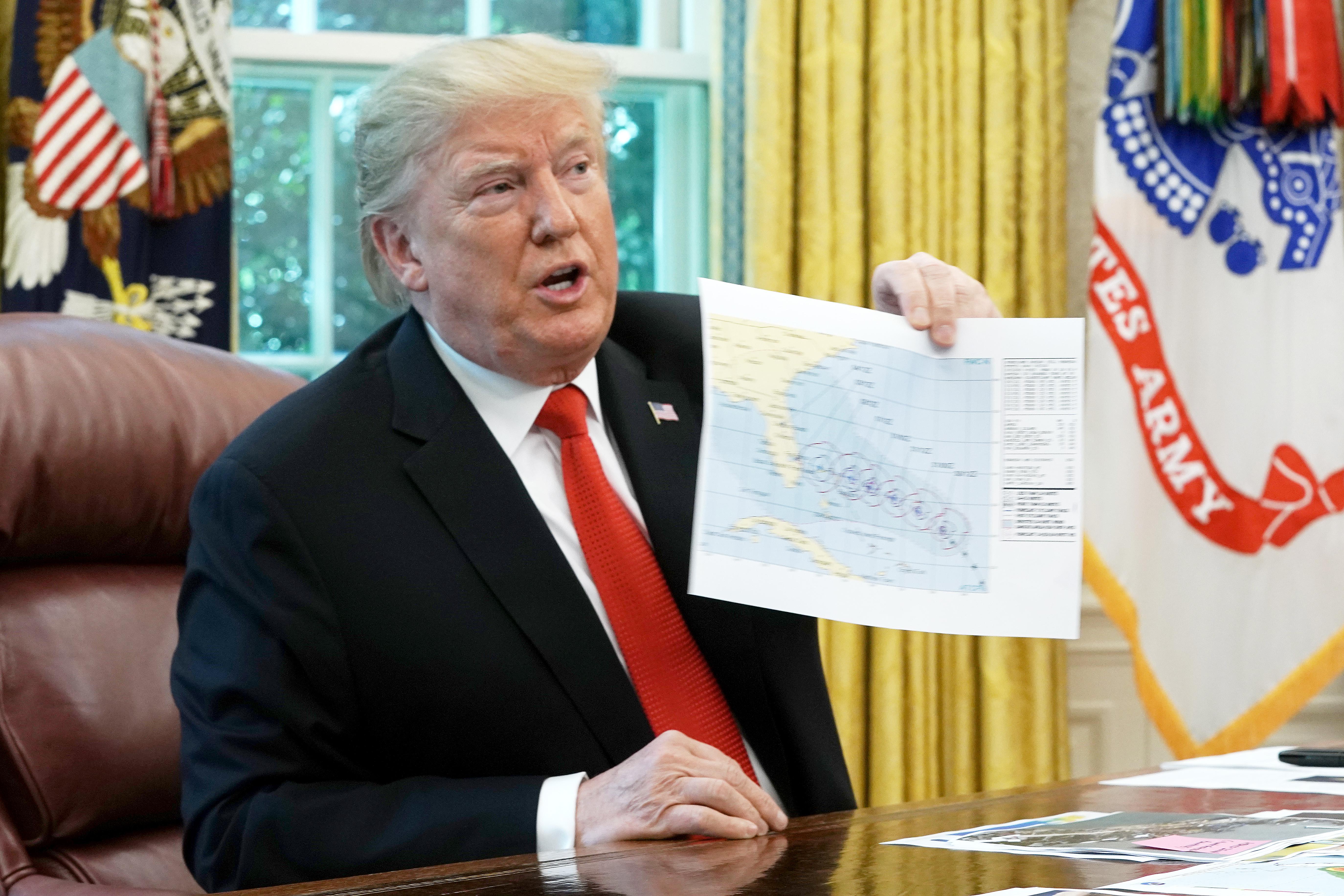 President Donald Trump shows reporters a map of a predicted path of Hurricane Dorian following a briefing from officials in the Oval Office at the White House September 4, 2019.