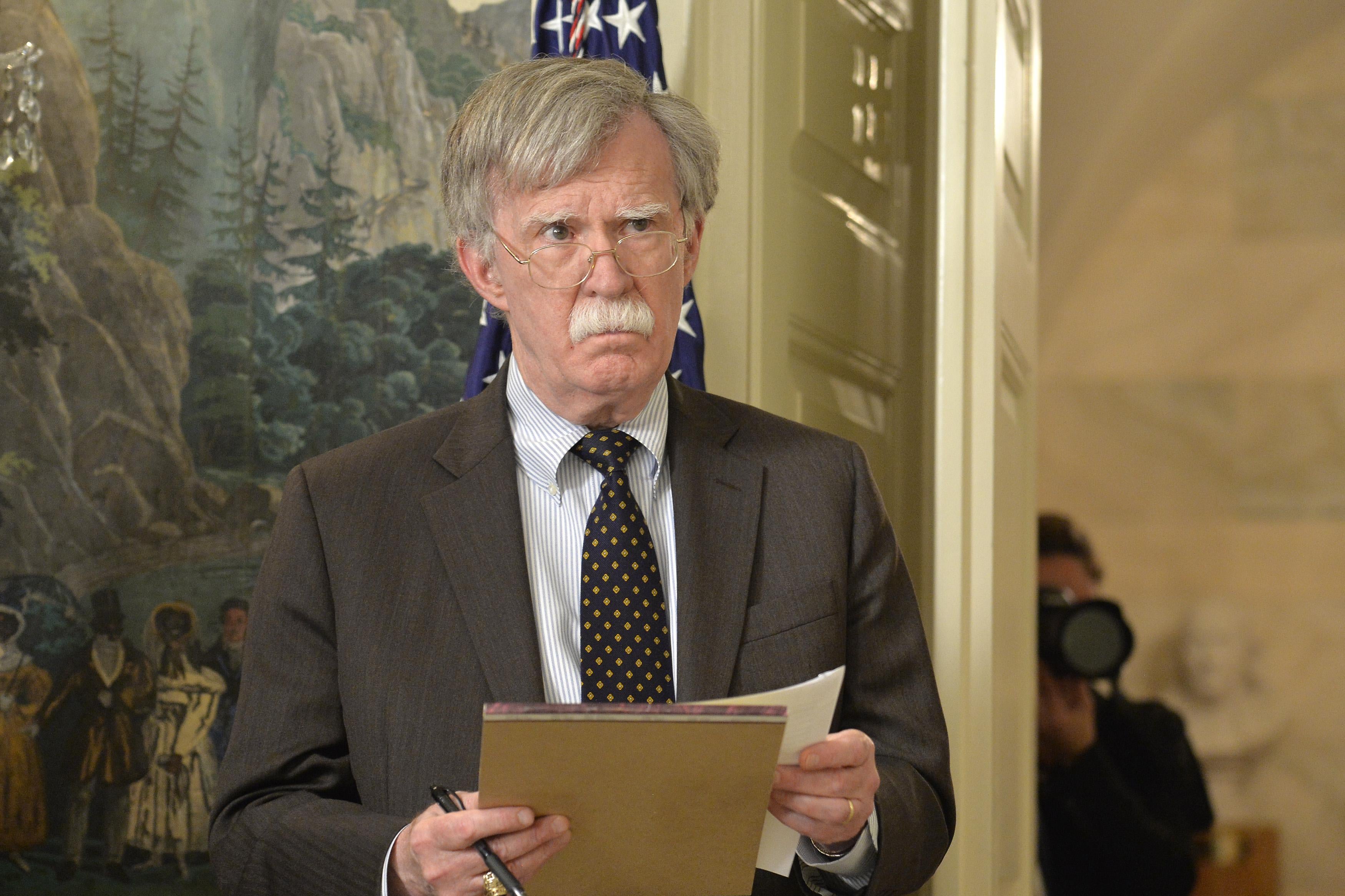 John Bolton holds a legal pad and pen.