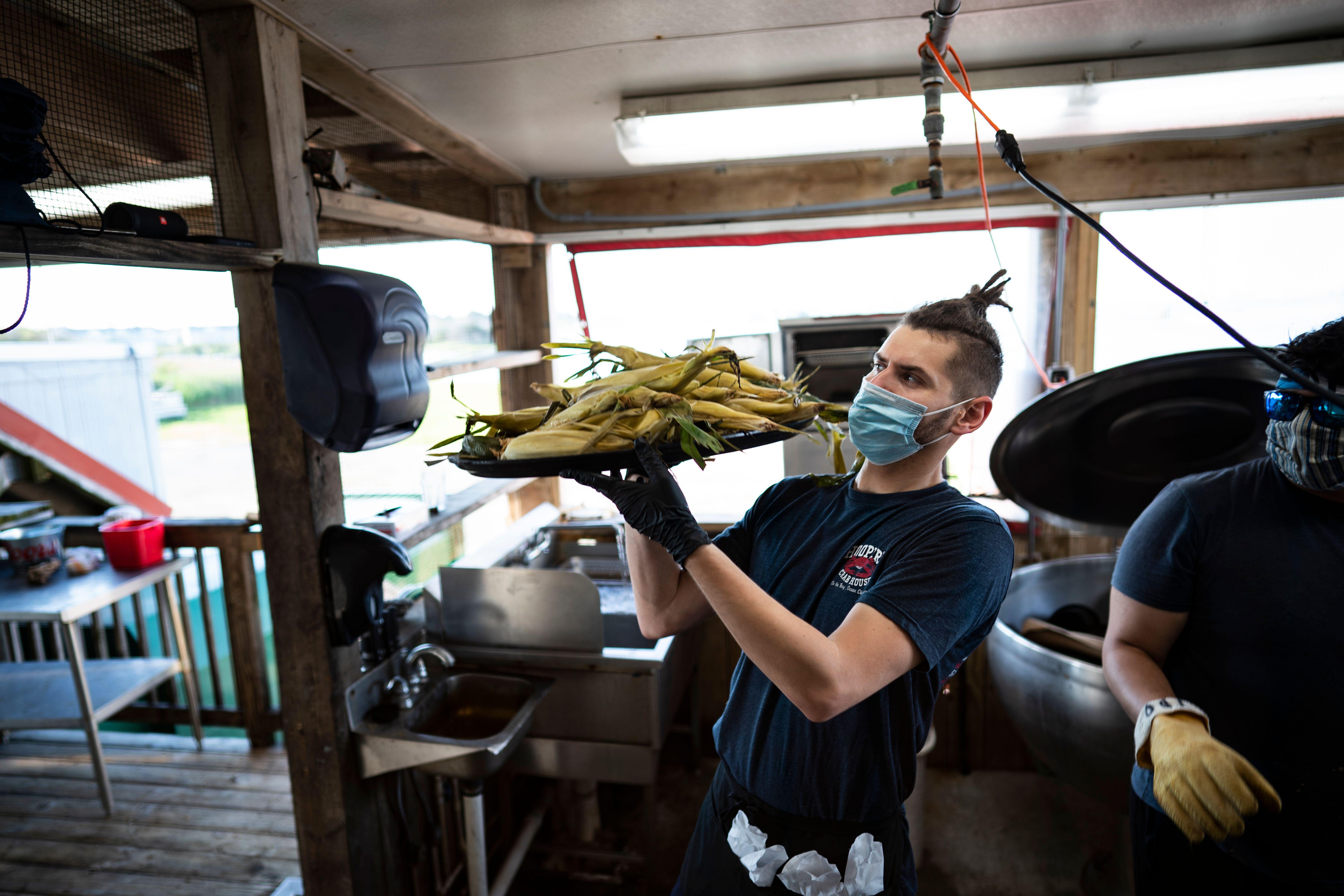 A server wears a mask and gloves while working, as Hoopers Crab House opens for in-person dining, amid the coronavirus pandemic, on May 30, 2020 in Ocean City, Maryland. - On the evening of May 29, 2020 restaurants and bars in the state of Maryland were opened for outdoor and open air dining. (Photo by Alex Edelman / AFP) (Photo by ALEX EDELMAN/AFP via Getty Images)