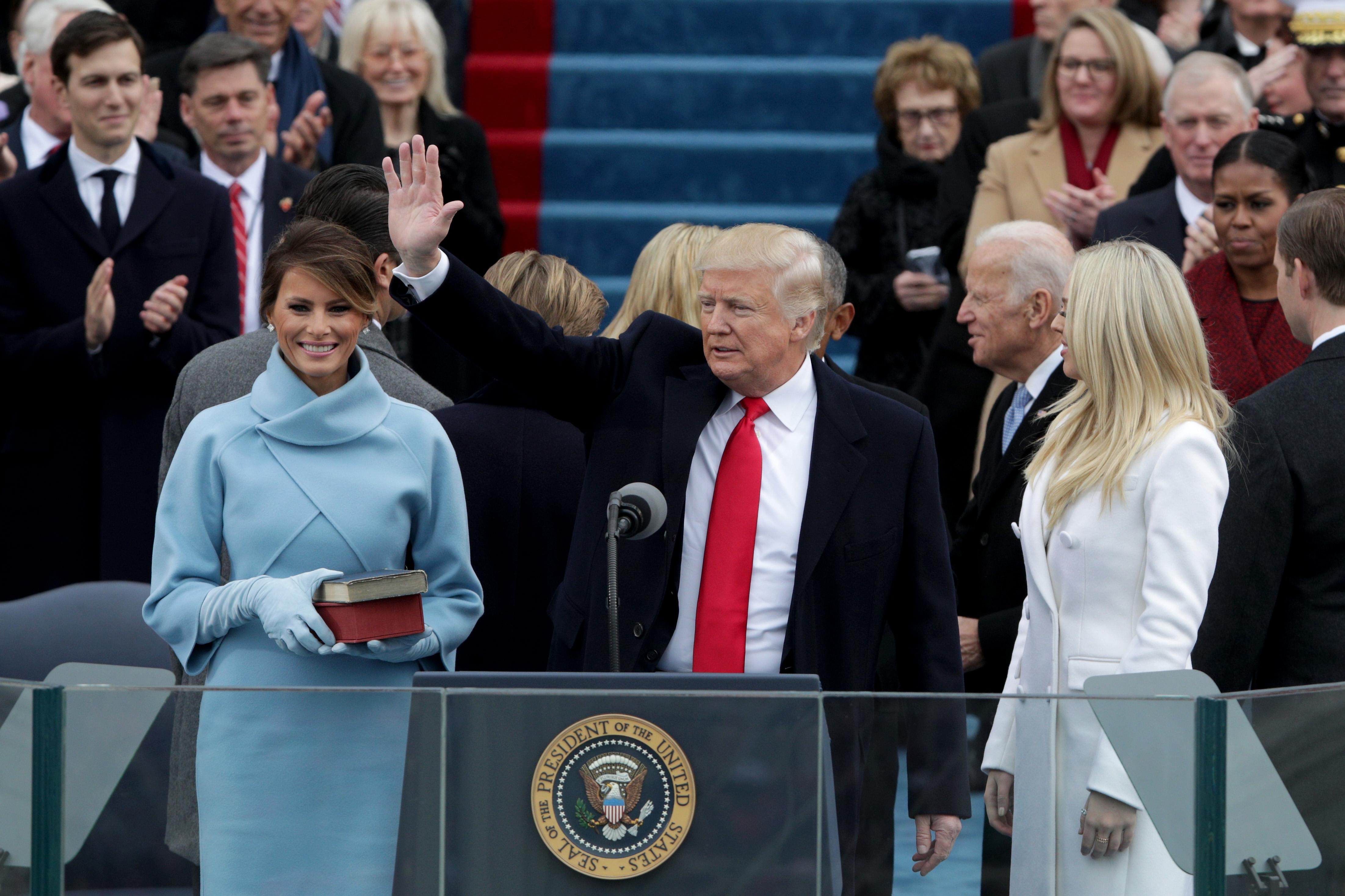 Trump waves at his inauguration. Melania stands next to him, holding books. On the other side, his daughter Tiffany looks around.