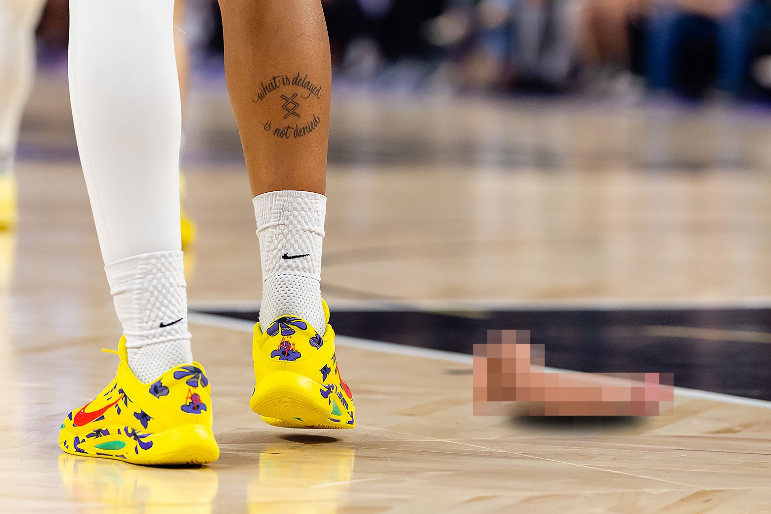 Rozmazany dildo-zabawka erotyczna na podłodze boiska WNBA obok stóp zawodniczki.