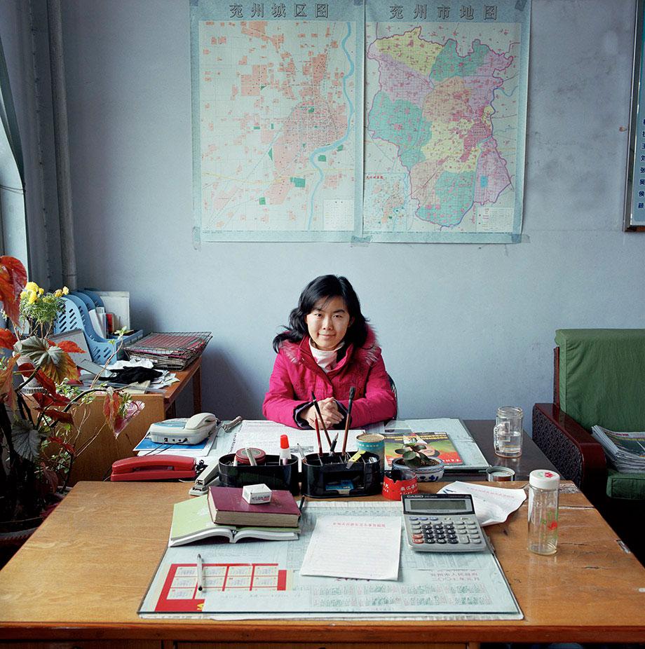 China, bureaucracy, (c) Jan Banning, 2007.Wang Ning (b. 1983) works in the Economic Affairs office in Gu Lou community, Yanzhou city, Shandong province. She provides economic assistance to enterprises in her region and is the liaison officer between the government and local enterprises: she helps them get a permit for land use, personnel insurances, environmental permits and taxation registration.There was (at the time) no heating in the room. The maps show regional industrial zones. Wang Ning is not married. She lives at home with her parents. She works from 8.30 to 12 am and from 14 to 16 am. She has no official paid holidays, except the national bank holidays and the weekends. Monthly salary: 2,100 renminbi ($ 260, euro 228).Wang Ning (1983) is adviseur op het Bureau voor Economische Zaken van Gu Lou, een wijk in de stad Yanzhou die valt onder de prefectuur Jining, provincie Shandong. Ze is een soort verbindingsofficier tussen de overheid en lokale ondernemingen: ze helpt hen aan vergunningen, aan info over de eisen w.b. administratie en werknemersrechten. Wang Ning is ongehuwd, ze woont bij haar ouders. Ze werkt vijf dagen per week van half negen tot twaalf en van twee tot vier uur. Ze heeft in oktober een week vakantie en drie dagen met Chinees Nieuwjaar. Maandsalaris: 2100 renminbi (€ 228, euro 228).